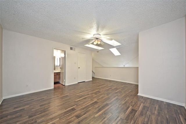 bonus room featuring a textured ceiling, lofted ceiling with skylight, ceiling fan, and dark hardwood / wood-style floors