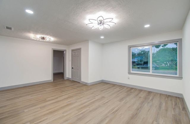 unfurnished room with a textured ceiling and light hardwood / wood-style floors