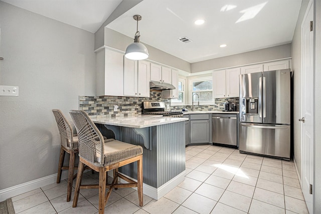 kitchen with kitchen peninsula, appliances with stainless steel finishes, sink, pendant lighting, and white cabinetry