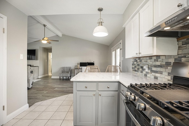 kitchen with kitchen peninsula, stainless steel gas range, exhaust hood, lofted ceiling with beams, and white cabinetry