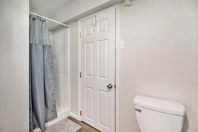 bathroom featuring wood-type flooring, toilet, and curtained shower