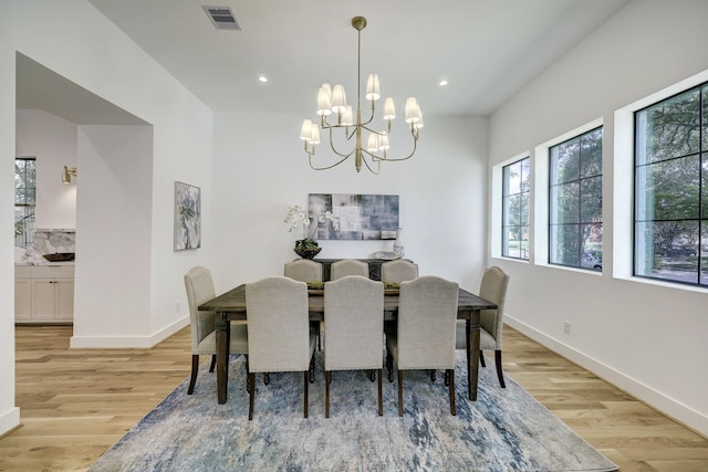 dining space with light hardwood / wood-style floors and a notable chandelier