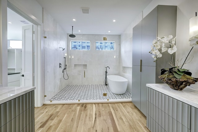 bathroom featuring hardwood / wood-style floors, tile walls, and independent shower and bath