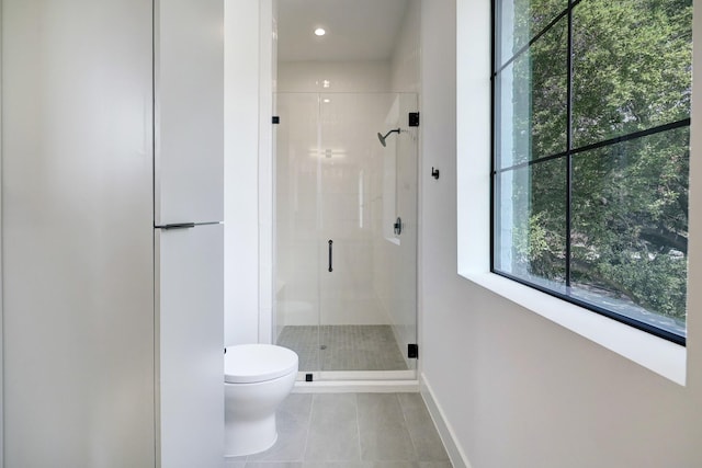 bathroom with tile patterned flooring, toilet, and a shower with shower door