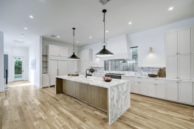 kitchen with light stone countertops, white cabinetry, pendant lighting, a spacious island, and high end appliances