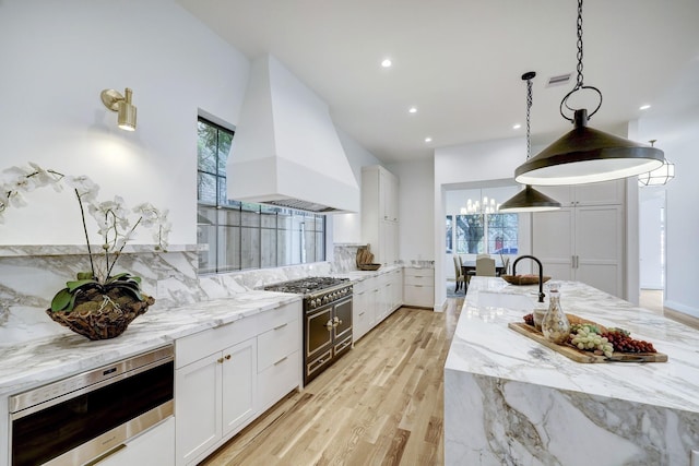 kitchen featuring decorative light fixtures, white cabinetry, and custom exhaust hood