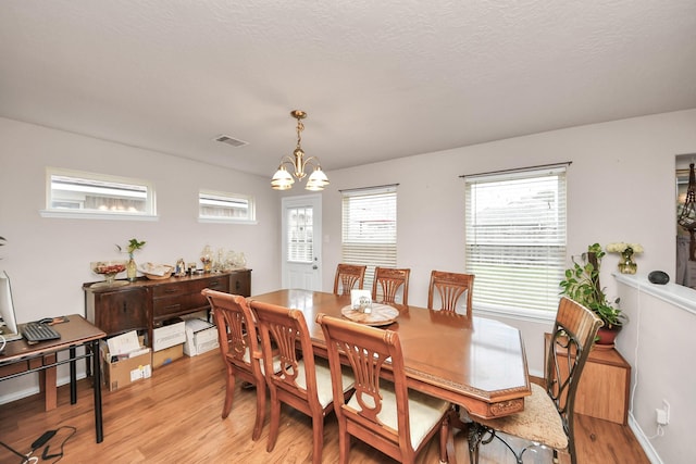 dining area featuring light wood-type flooring and a notable chandelier