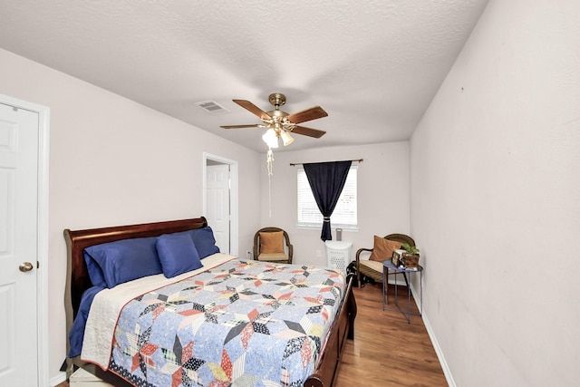 bedroom with hardwood / wood-style flooring, ceiling fan, and a textured ceiling