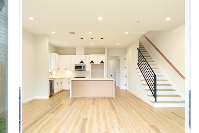 kitchen featuring hanging light fixtures, stainless steel appliances, a center island, and white cabinets