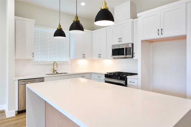 kitchen featuring a kitchen island, decorative light fixtures, white cabinetry, sink, and stainless steel appliances