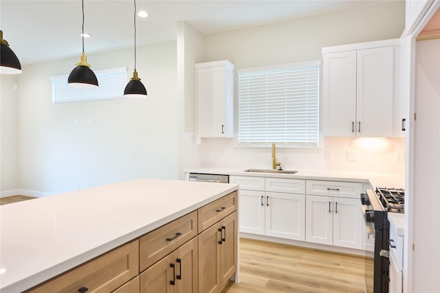 kitchen with stainless steel range with gas cooktop, decorative light fixtures, sink, and white cabinets