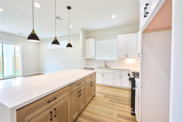 kitchen with white cabinetry, sink, pendant lighting, and high end stove