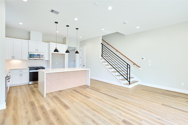 kitchen featuring a center island, light hardwood / wood-style flooring, appliances with stainless steel finishes, pendant lighting, and white cabinets