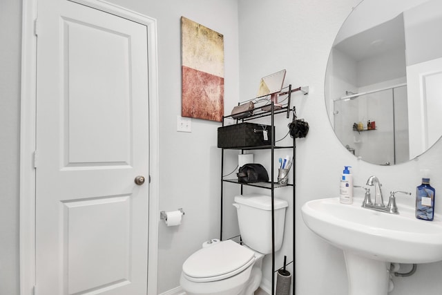 bathroom with a shower with shower door, sink, and toilet