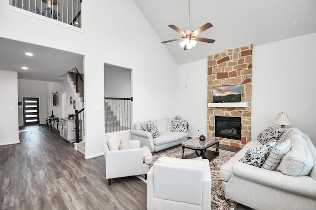 living room featuring high vaulted ceiling, ceiling fan, a fireplace, and dark wood-type flooring