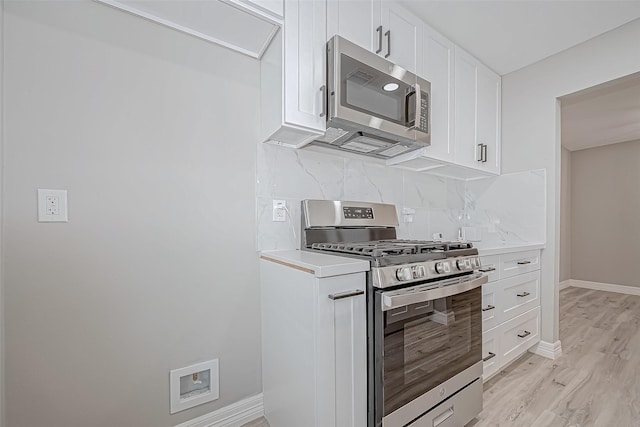 kitchen with decorative backsplash, light hardwood / wood-style flooring, white cabinets, and appliances with stainless steel finishes