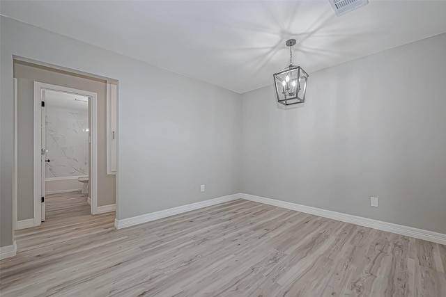 unfurnished room featuring light wood-type flooring and a notable chandelier