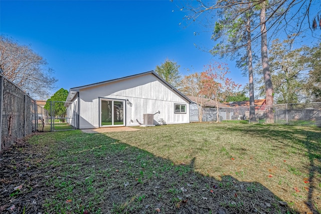 back of property with central AC unit and a yard