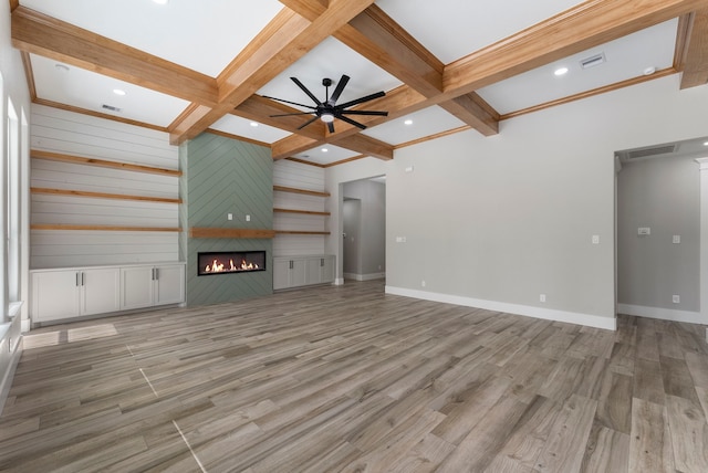 unfurnished living room featuring beam ceiling, a large fireplace, wood-type flooring, and coffered ceiling