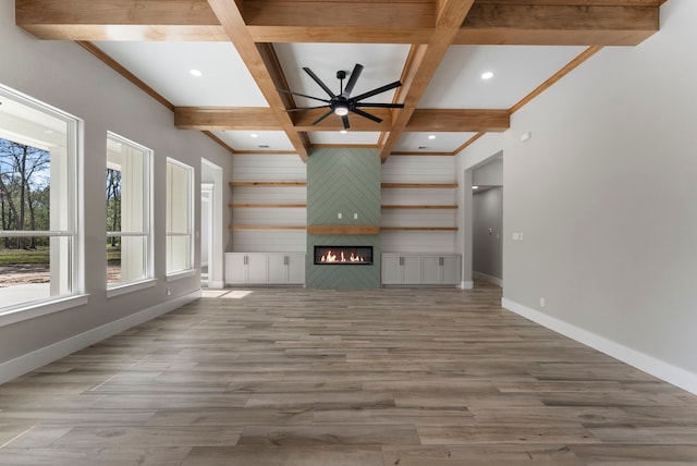 unfurnished living room featuring coffered ceiling, a large fireplace, ceiling fan, wood-type flooring, and beam ceiling