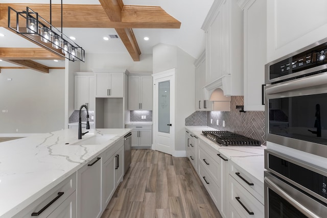 kitchen with white cabinets, beam ceiling, and light stone counters