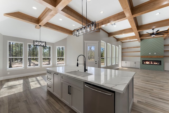 kitchen featuring dishwasher, sink, pendant lighting, a fireplace, and a center island with sink