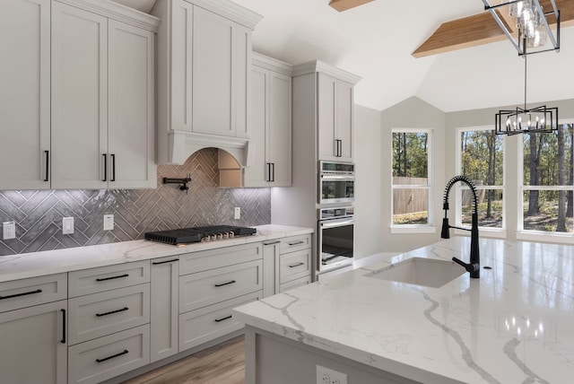 kitchen featuring light stone countertops, sink, stainless steel appliances, and decorative light fixtures