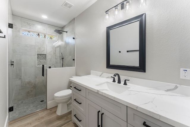 bathroom featuring vanity, wood-type flooring, an enclosed shower, and toilet