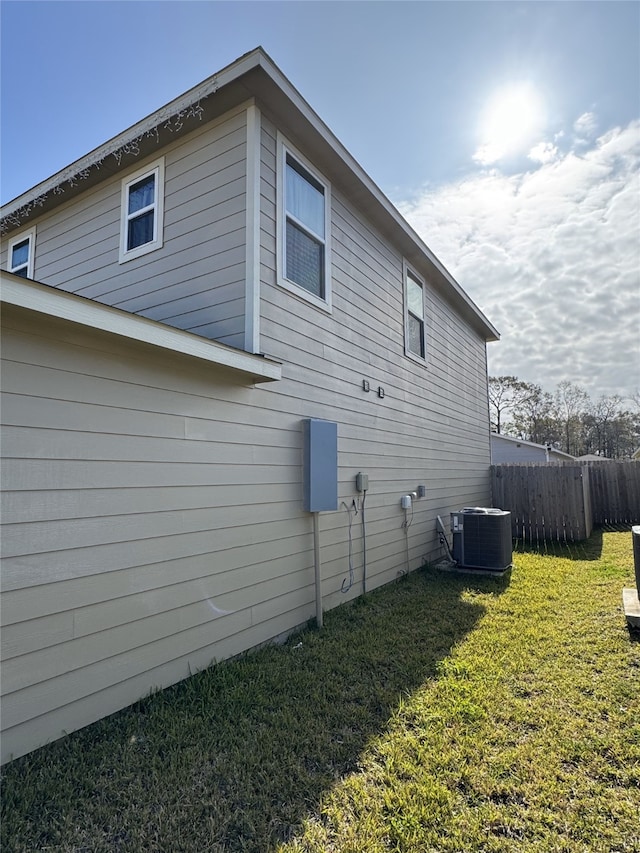 view of side of property featuring a lawn and cooling unit