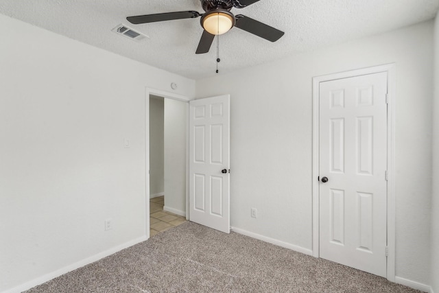 unfurnished bedroom with a textured ceiling, light colored carpet, and ceiling fan