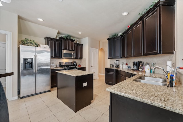 kitchen featuring sink, a center island, light stone counters, light tile patterned flooring, and appliances with stainless steel finishes