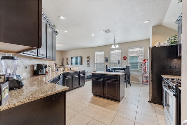 kitchen with tasteful backsplash, decorative light fixtures, a chandelier, stainless steel gas stove, and a kitchen island