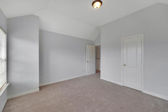 spare room with light colored carpet and lofted ceiling