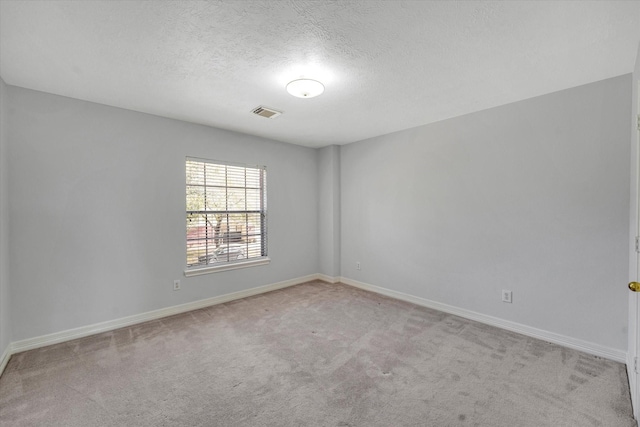 spare room featuring a textured ceiling and light colored carpet