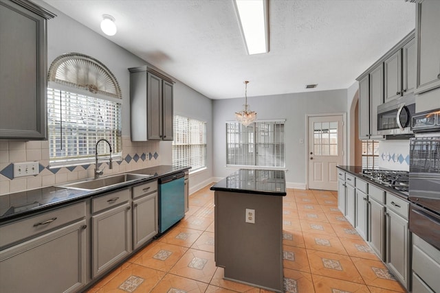 kitchen featuring a wealth of natural light, stainless steel appliances, sink, gray cabinets, and a kitchen island