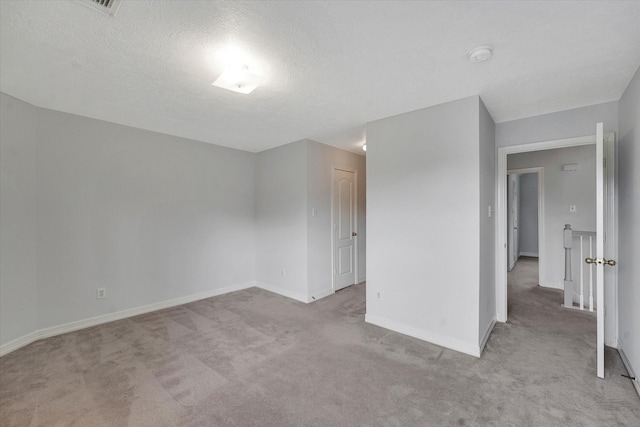 empty room featuring light colored carpet and a textured ceiling