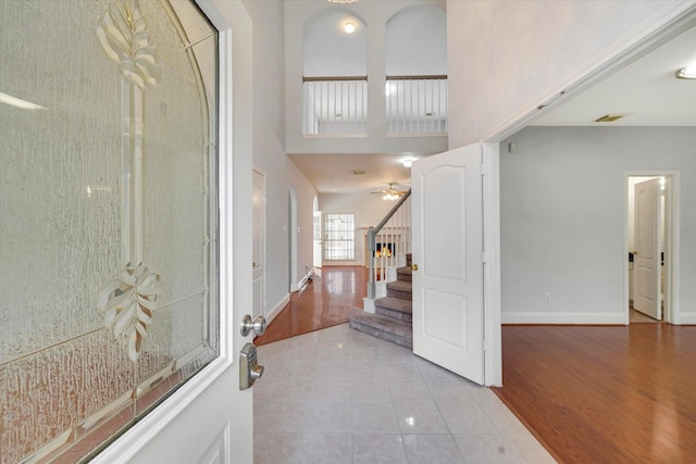 tiled entryway featuring ceiling fan and a towering ceiling