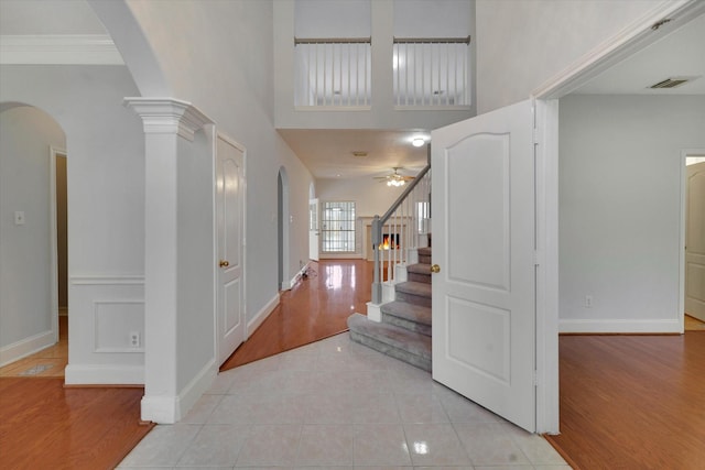 tiled foyer entrance with ceiling fan and crown molding