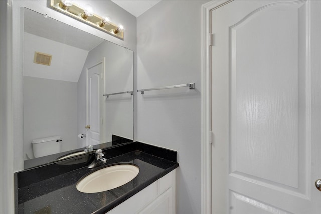 bathroom featuring vanity, lofted ceiling, and toilet