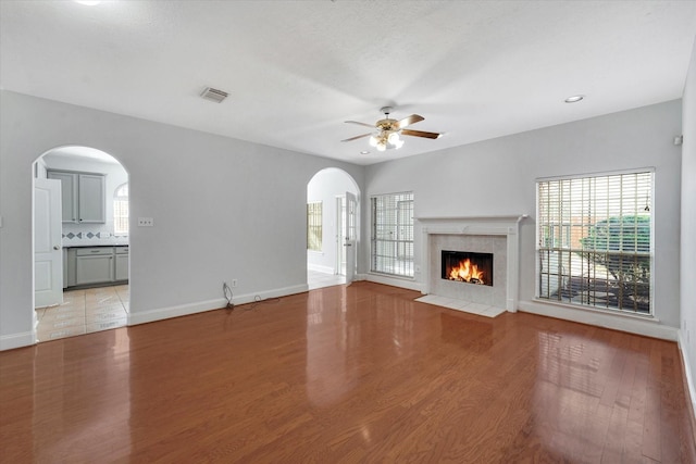 unfurnished living room with ceiling fan, light wood-type flooring, and a fireplace