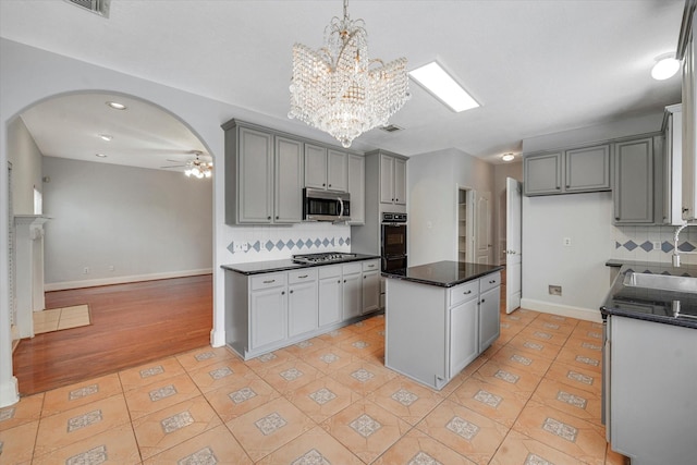 kitchen with gray cabinetry, a center island, stainless steel appliances, and tasteful backsplash