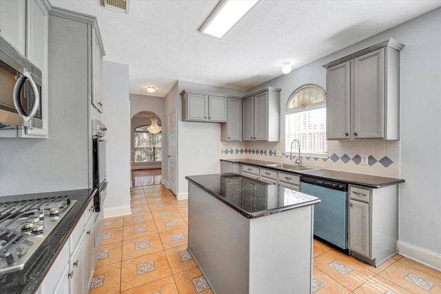 kitchen with a center island, sink, appliances with stainless steel finishes, tasteful backsplash, and light tile patterned flooring