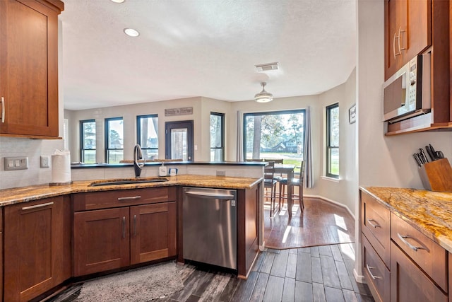 kitchen with dishwasher, dark hardwood / wood-style flooring, light stone counters, and sink