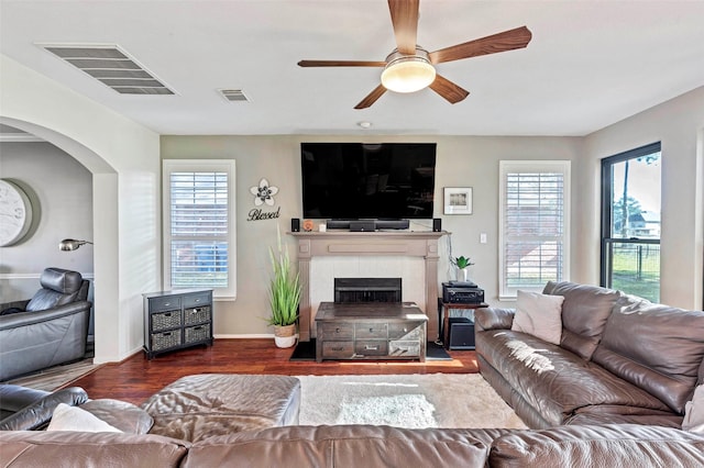 living room with dark hardwood / wood-style floors, ceiling fan, plenty of natural light, and a tiled fireplace