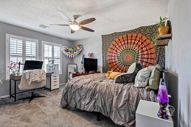 carpeted bedroom featuring ceiling fan and a textured ceiling