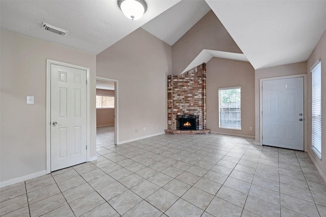 unfurnished living room with a brick fireplace, light tile patterned floors, and vaulted ceiling