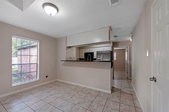 kitchen featuring stainless steel fridge, light tile patterned flooring, white cabinets, and kitchen peninsula