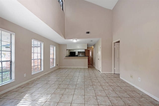 unfurnished living room featuring light tile patterned flooring and a high ceiling