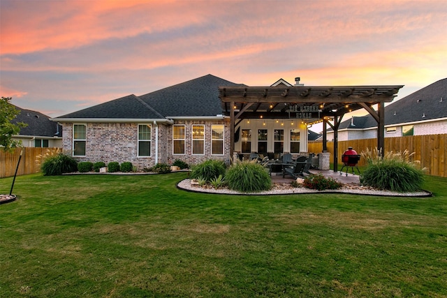 back house at dusk featuring a lawn, a pergola, and a patio