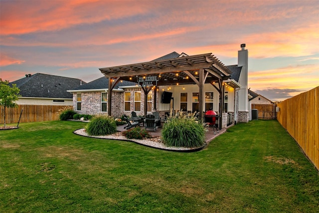 back house at dusk featuring a lawn, a patio area, and a pergola